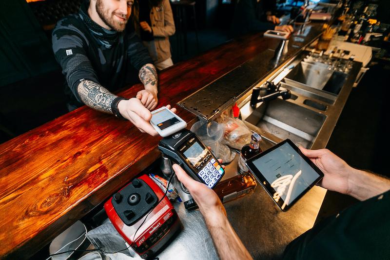 Bartender is taking payment at the bar counter